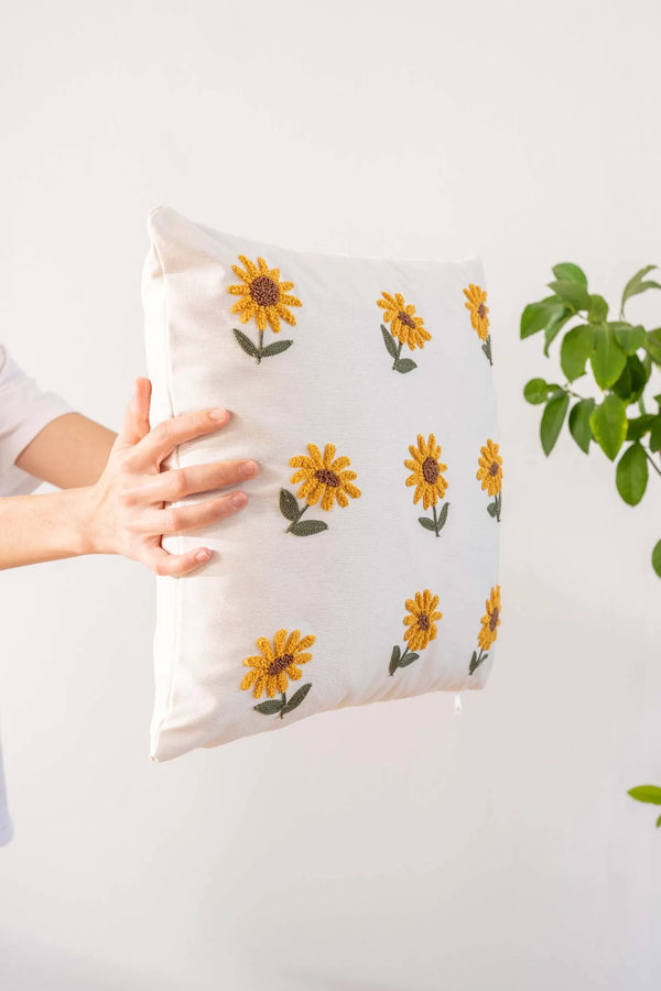 Cremefarbener Hintergrund, Sonnenblumenmuster, dekorativer Leinenkissenbezug mit Lochstickerei.