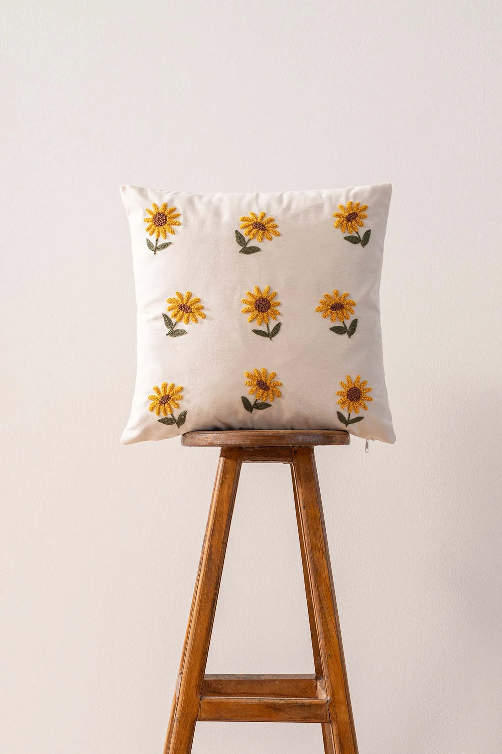 Cremefarbener Hintergrund, Sonnenblumenmuster, dekorativer Leinenkissenbezug mit Lochstickerei.